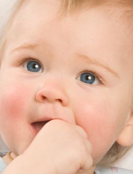 Portrait of the one-year-old girl close up, sucking the hand
