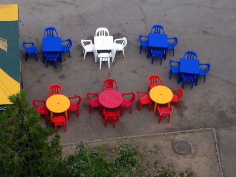 Varicoloured tables and chair of summer cafe, view overhand.