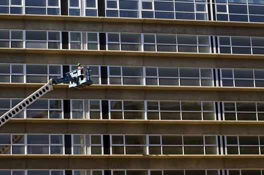 Maintenance worker in a crane inspecting a new residential building