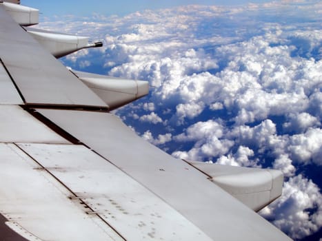 An airplane wing flying at high altitude above the clouds.Great ad for any travel company          