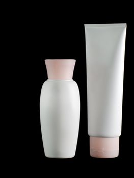 White tubes of a cream with pink covers on a black background