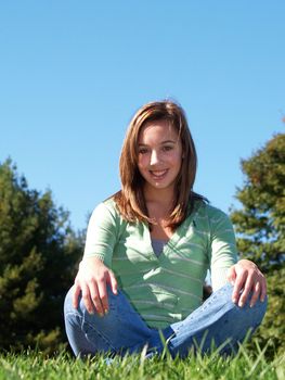 teenage girl sitting in the grass on a sunny day