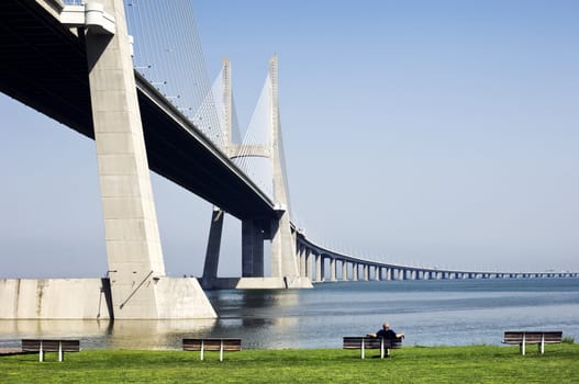 Lone man relaxing near the Vasco da Gama Bridge, Portugal