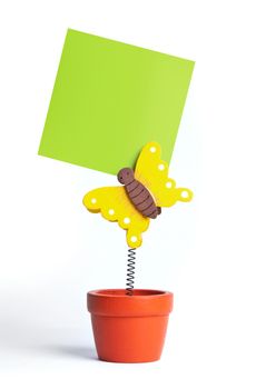 Isolated image of green notepaper attached by a butterfly toy in flowerpot