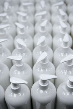 White plastic soap bottles in rows, cosmetics laboratory assembly line