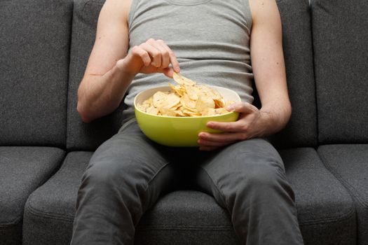 A man on a couch eating potato chips