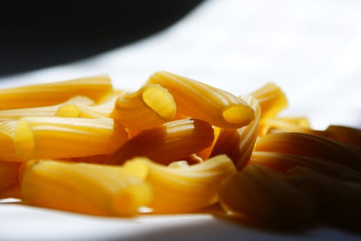 raw macaroni scattered against black and white background