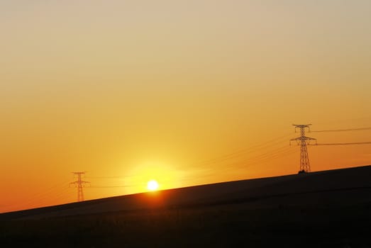 high voltage pylons and sunset background