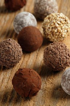 An assortment of chocolate truffles on old wood table.  Very Shallow depth of field, focusing on middle truffle.
