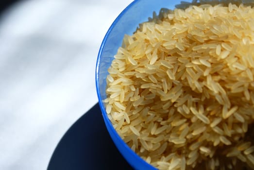 blue saucer with raw rice against white background