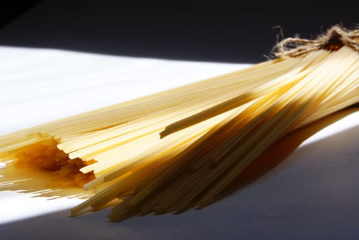 spaghetti pasta sunlit and tied against light and shadow background
