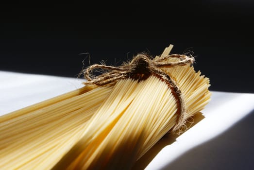 spaghetti pasta tied and sunlit against light and shadow background