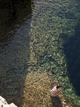 Young Woman looking over the reef in the Blue Hole in Gozo in Malta