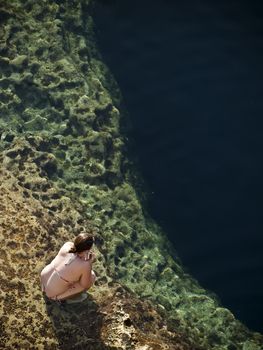 Young Woman looking over the reef in the Blue Hole in Gozo in Malta