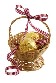 Two chocolate eggs wrapped  golden foil in Easter straw interwoven basket decorated with ribbon isolated on white background
