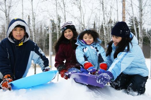 Four kids enjoying winter outdoors sledding