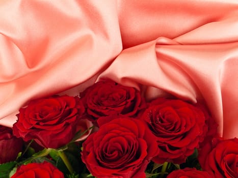 Red beautiful roses on a pink silk fabric 
