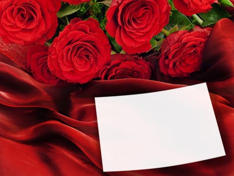 red roses with white greeting card at vinous fabric