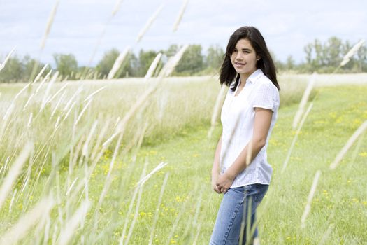 Beautiful teen girl in grassy field in summer