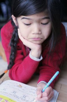 Little girl frowning while doing homework