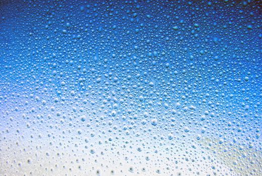 Water drop on a window in blue sky background 