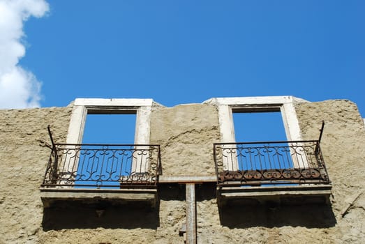 rusty building facade with two empty windows/balconies