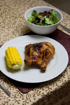 Plate of roast chicken with corn, salad and red wine