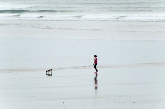 woman walking the dog by the beach