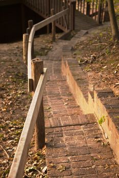 curved brick paved stairs with wood railing down to wood foot bridge