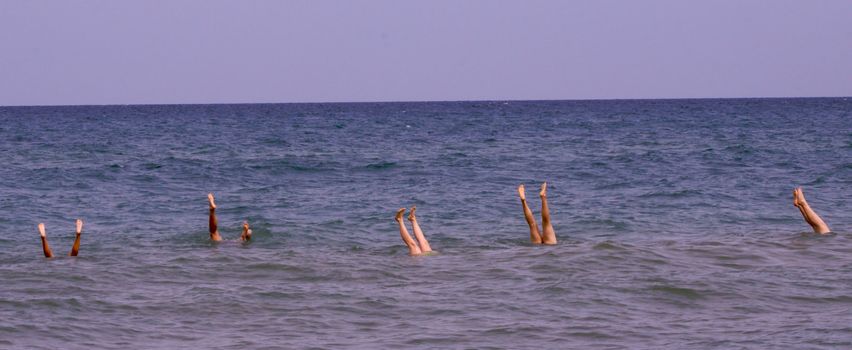 five girls doing attempted handstand on a sandbar in lake michigan