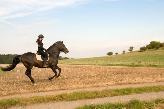 Equestrienne rides at a gallop across the field.