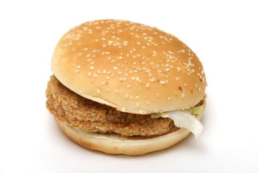 An isolated chicken burger on a sesame seed bun.