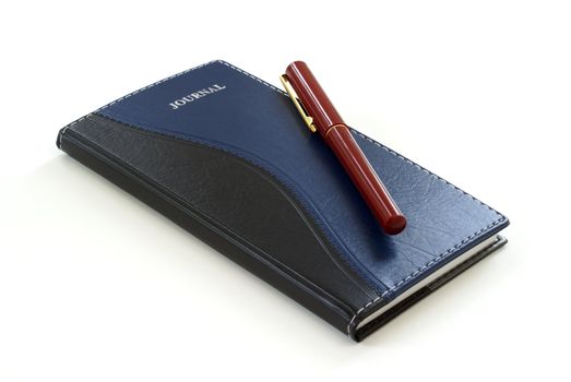 A pen sits on a leather journal.