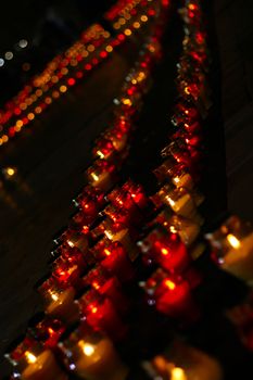 Big beautiful row of red funeral candles shot at night with shallow depth of field and blurred background