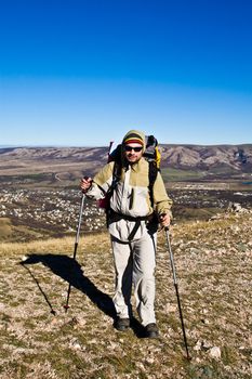 Hiker with hiking poles walks in mountains