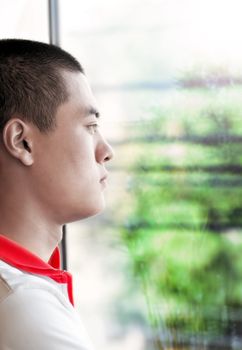A Chinese young man looking on the window