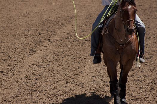 A cowbo on horse back in the middle of a dirt ranch or arena.