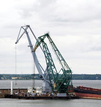 Two floating cranes are at a mooring in harbour