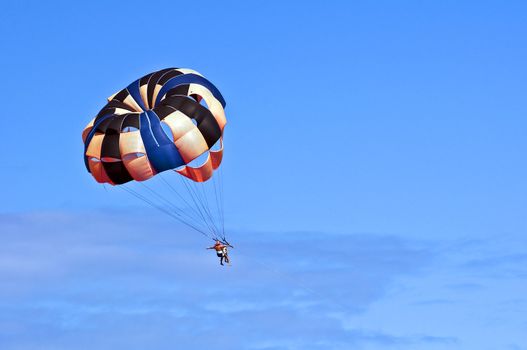 Photo of two people parasailing under blue sky.