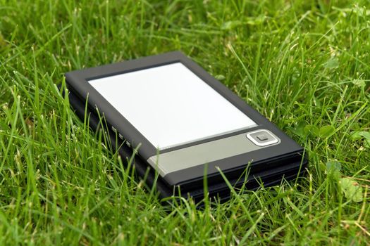 Portable electronic book lying on the grass.