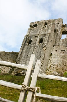 Corfe Castle in Dorset shot at a low angle with focus on a wooden gate to the foreground.