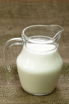 Milk jug on brown background