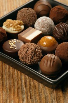 A small assortment of chocolate truffles and pralines on a serving dish.  Very Shallow depth of field, focusing across the middle.

