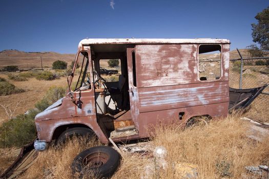 An old abandoned vintage delivery truck van in a field