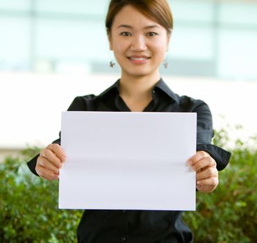 Young asian business woman holding a blank white paper for text