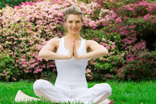 Blonde girl in nature green park exercising yoga, fitness program