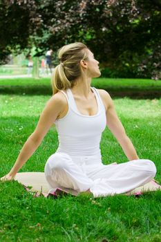 Blonde girl in nature green park exercising yoga, fitness program