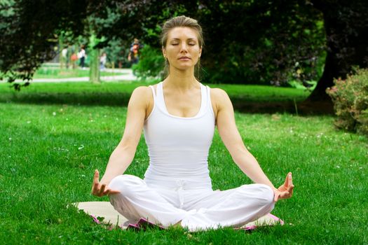 Blonde girl in nature green park exercising yoga, fitness program