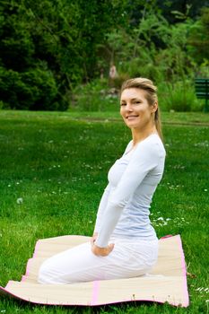 Blonde girl in nature green park exercising yoga, fitness program