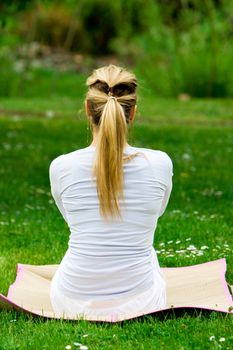 Blonde girl in nature green park exercising yoga, fitness program